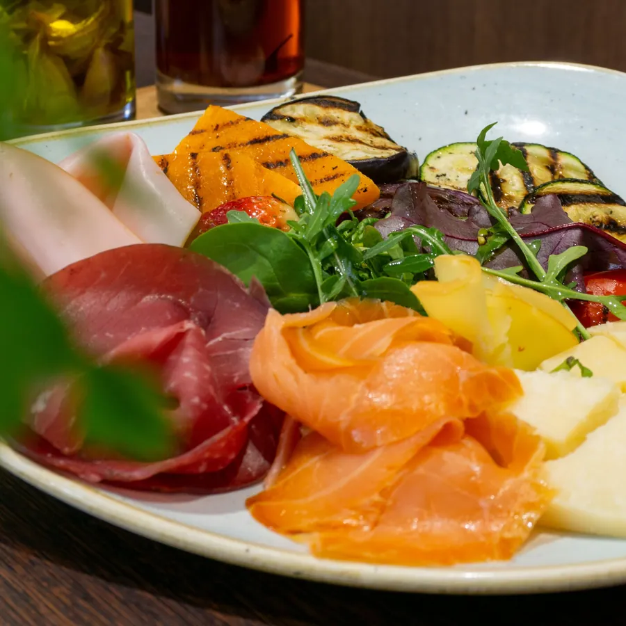 Antipasti-Teller mit Bresaola, Lachs, Käse und gegrilltem Gemüse.