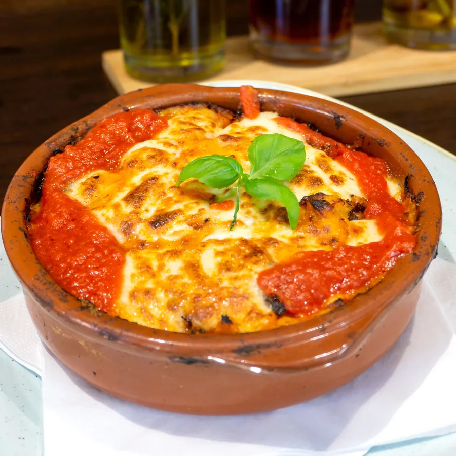 Überbackene Pasta in der Tonform mit Tomatensauce und Basilikum.